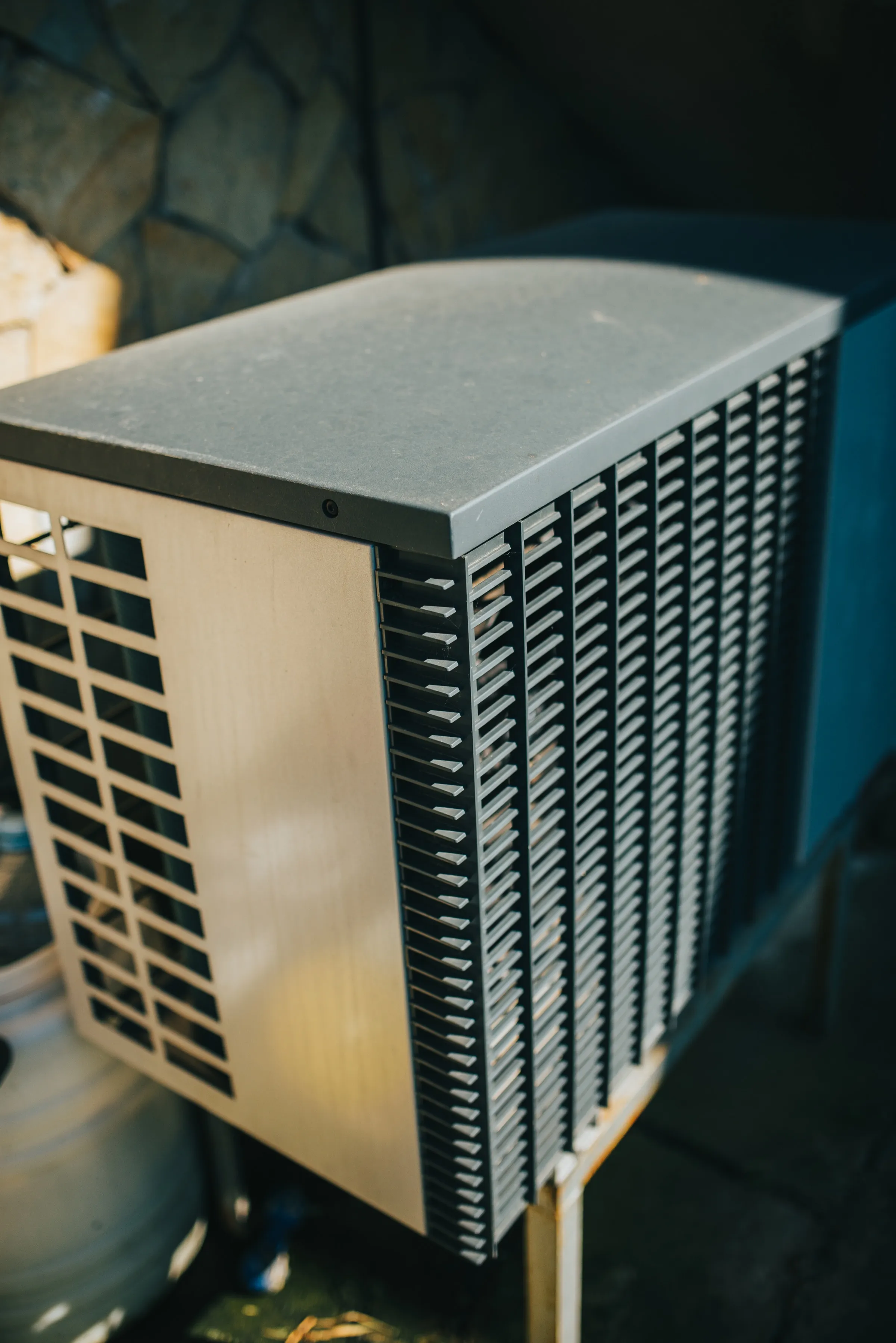 An air source heat pump installed against the wall of a house
