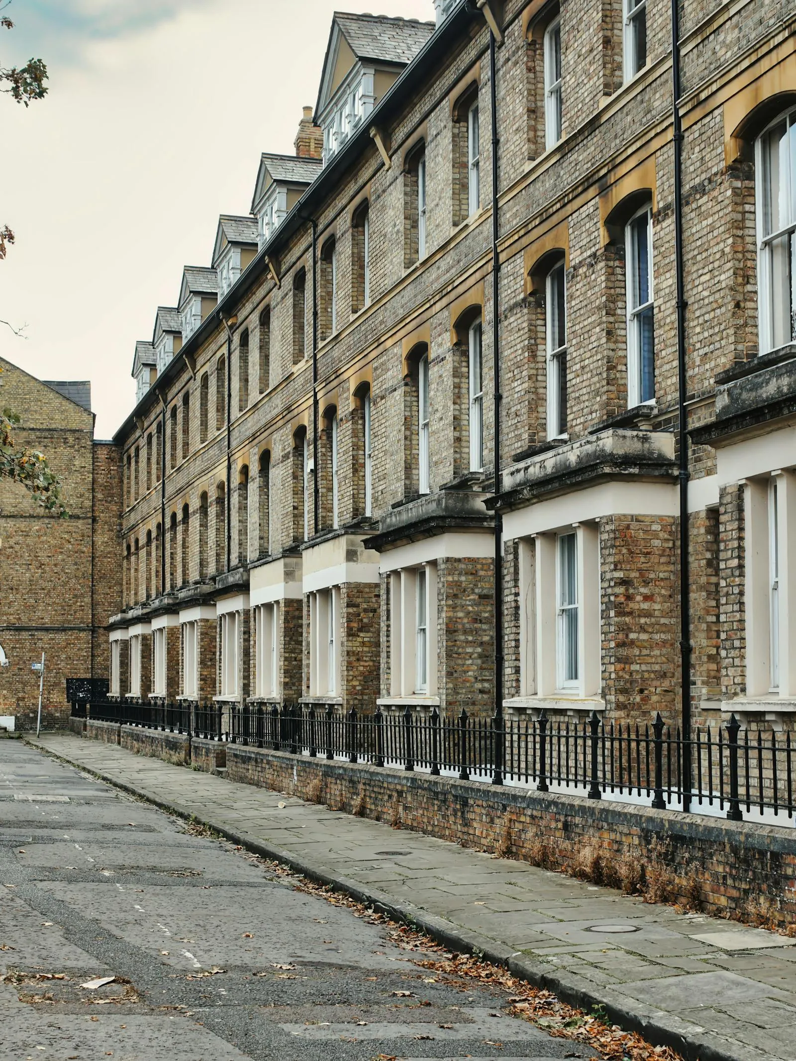 A long terrace of yellow-brick Victorian houses with sash windows and iron railings — typical of the period housing stock found across Cambridge's older neighbourhoods