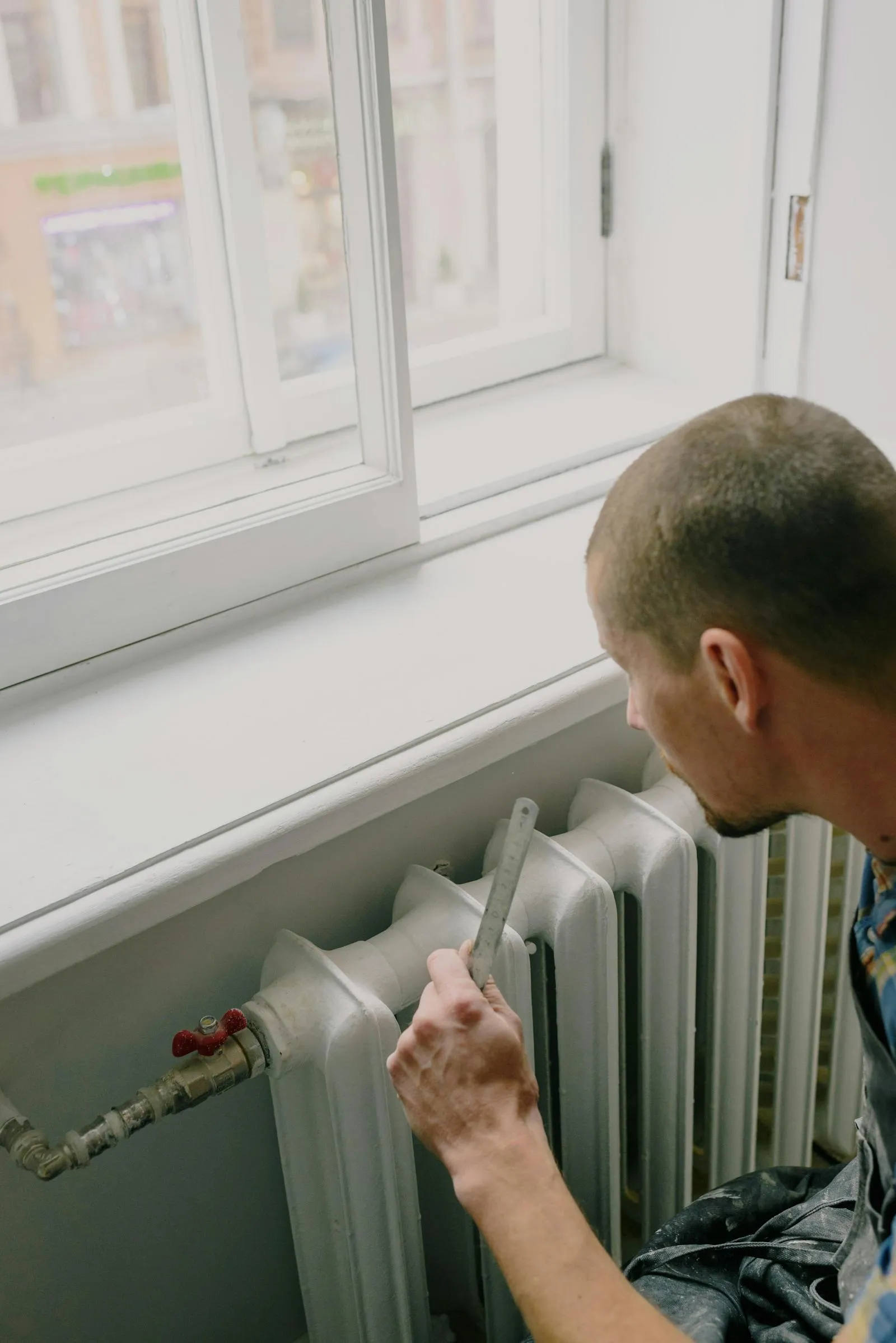 An engineer measuring a cast-iron radiator as part of a heat pump design