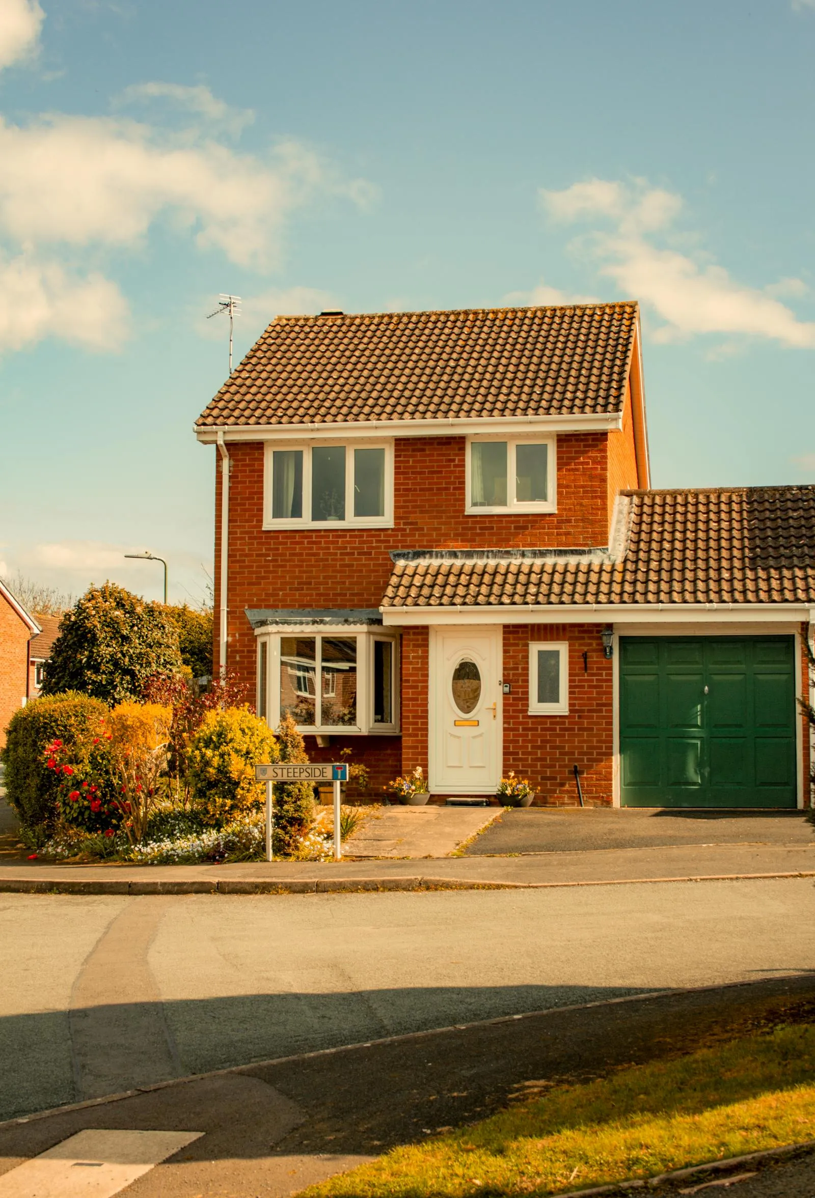 A red-brick detached UK home with a tile-clad bay window and attached garage — modern suburban housing stock typical of the kind found across Cambridge neighbourhoods including parts of Chesterton.