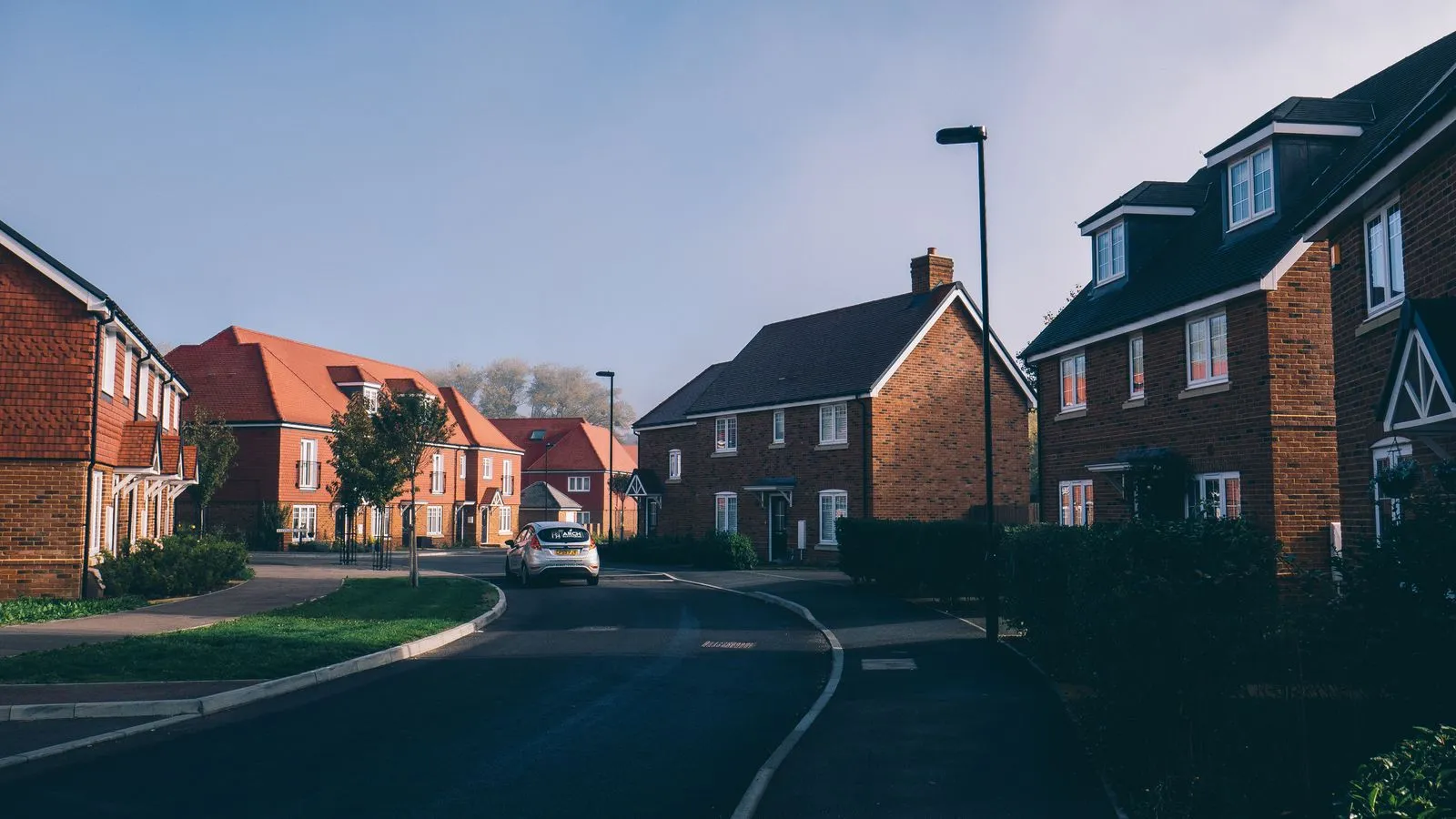 A modern new-build red-brick UK estate at sunset — modern suburban stock representative of the recent development around the southern Cambridge edge, including parts of Trumpington.